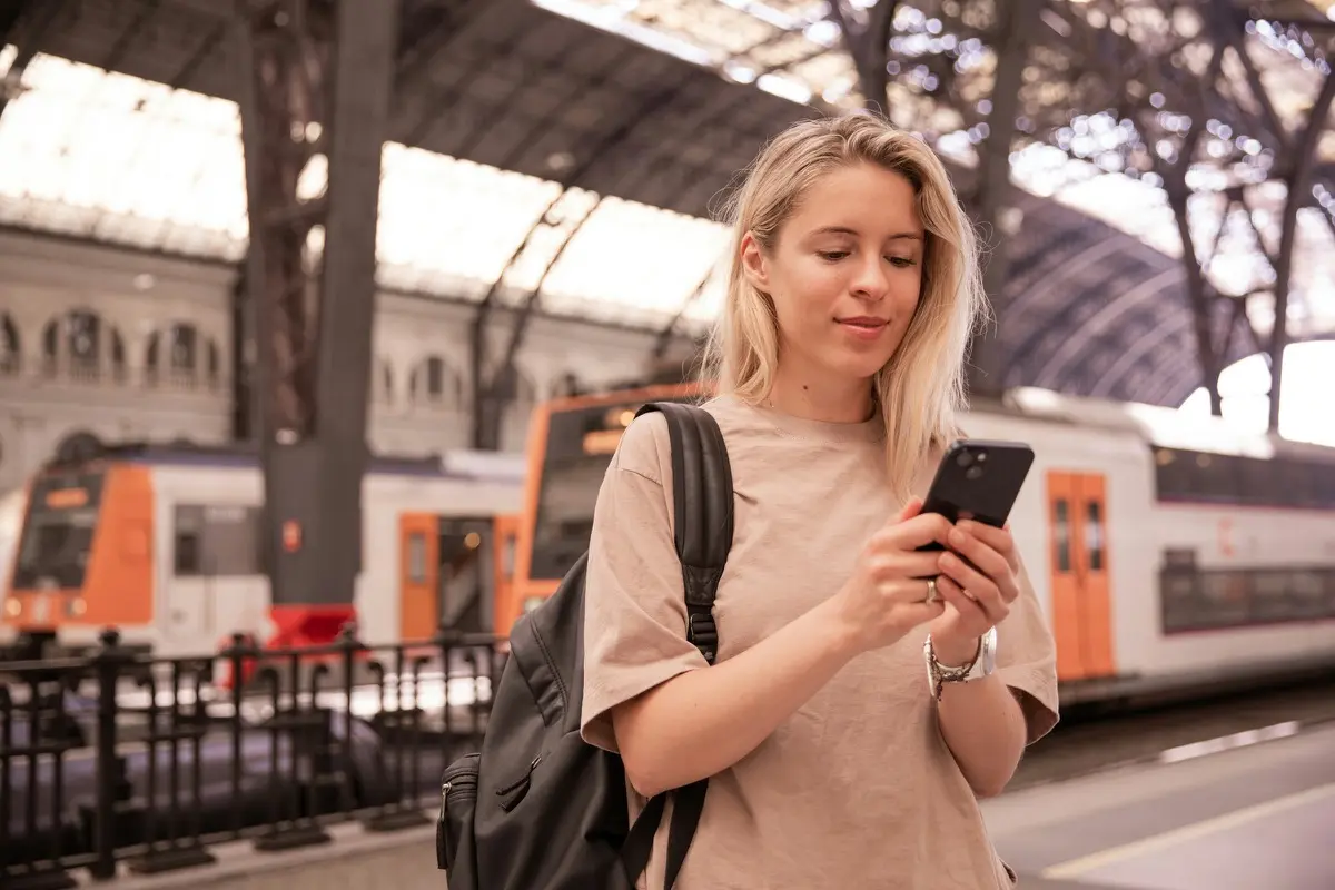 Traveler checking her phone at a train station while abroad