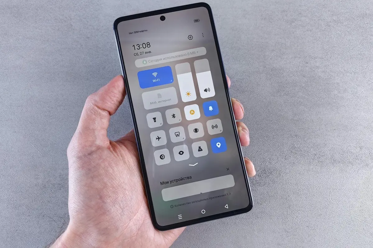 Hand holding smartphone displaying settings and quick controls panel