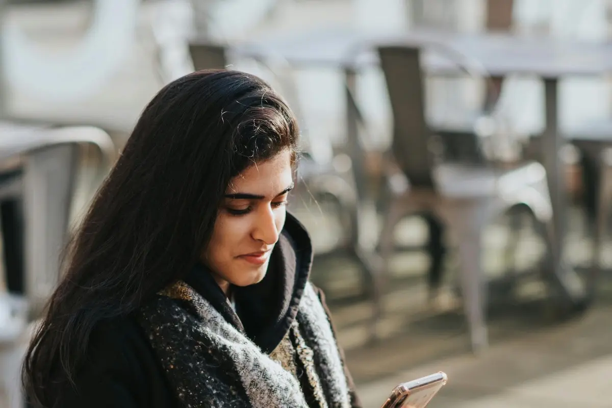 Woman browsing on her phone at an outdoor cafe while traveling