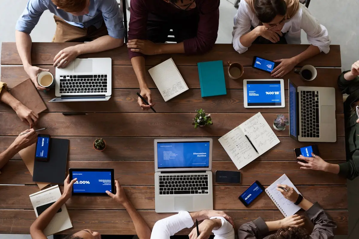 People collaborating at a table with phones and laptops