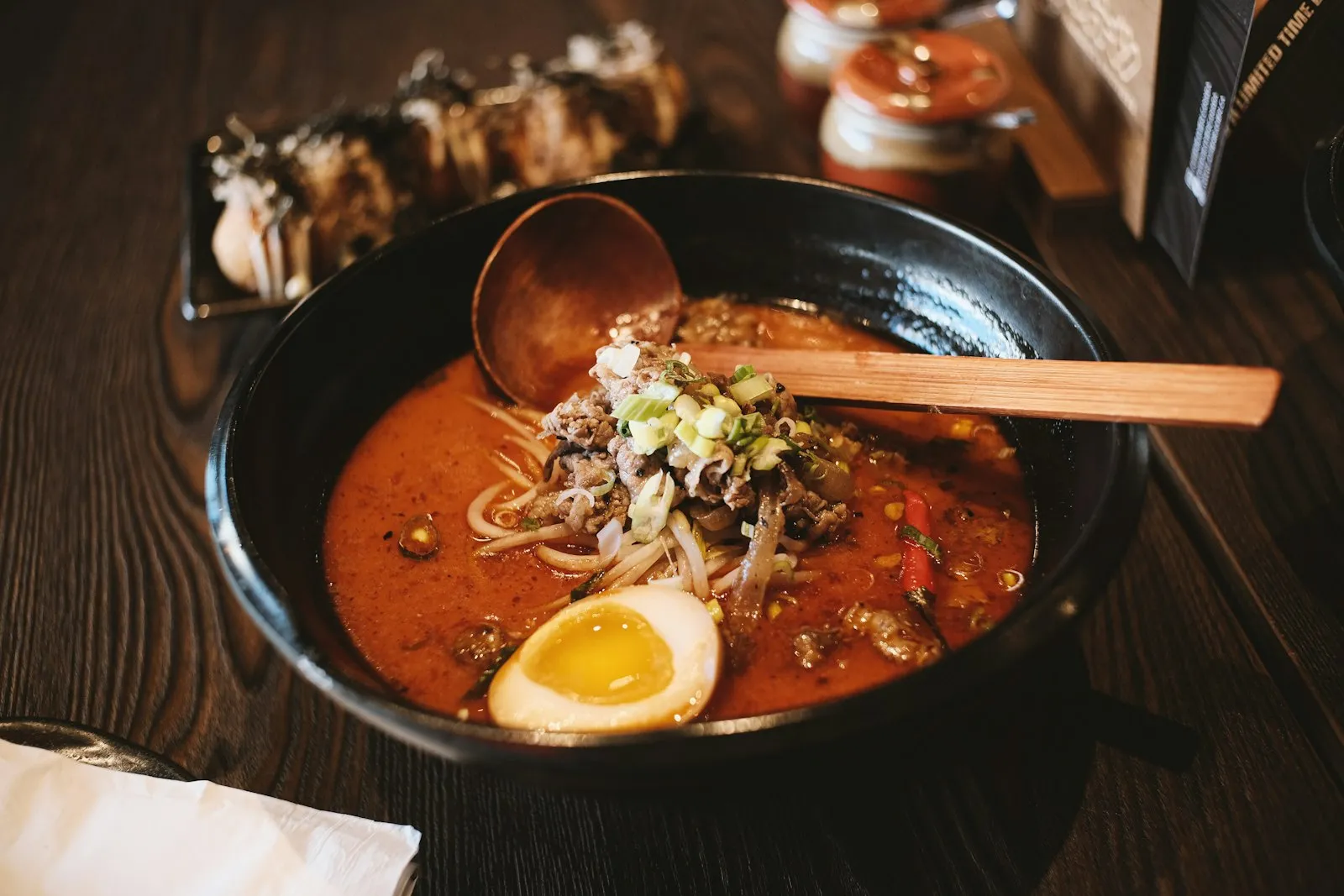 Steaming bowl of Japanese ramen with soft-boiled egg, sliced pork, nori, and fresh vegetables