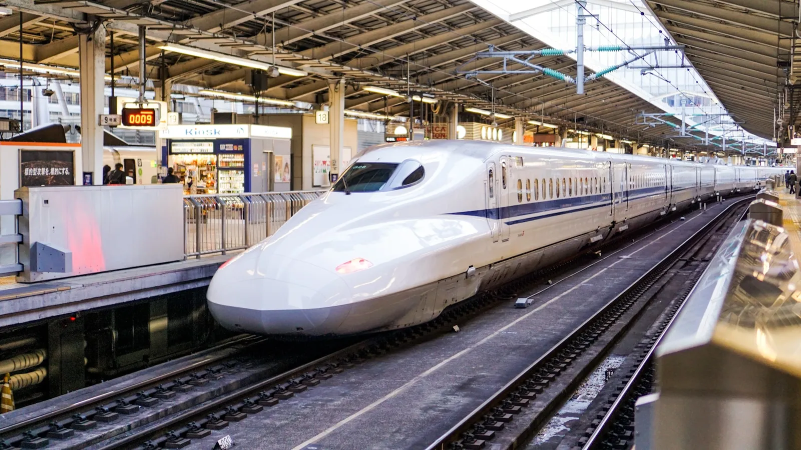 White Shinkansen bullet train speeding through a station in a motion blur