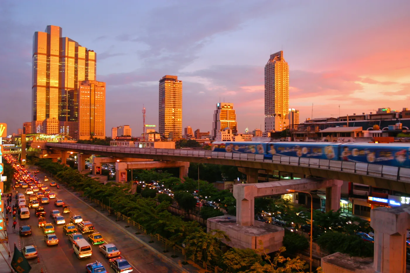 Bangkok skytrain running past high-rise buildings at sunset