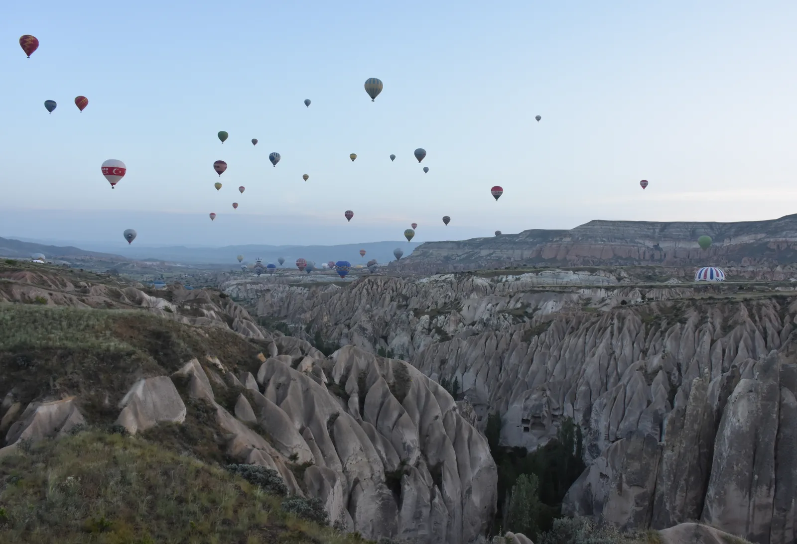 Hot air balloons over valleys near Goreme in Cappadocia at dawn