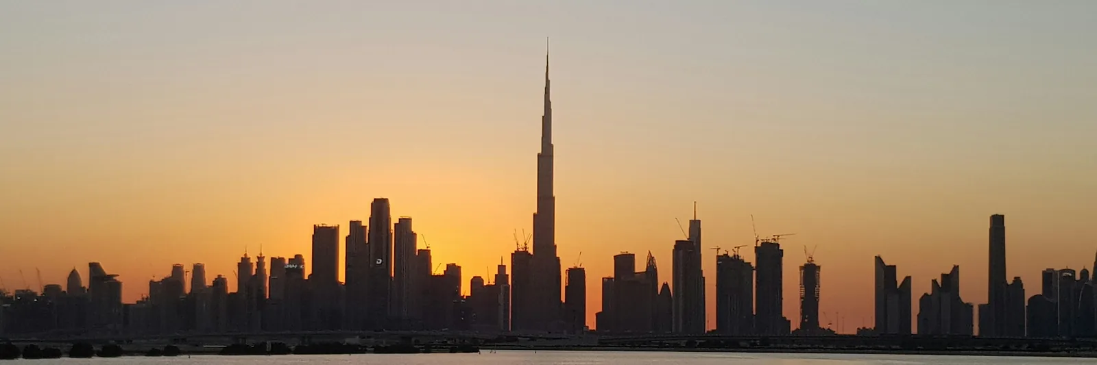 The Burj Khalifa and Dubai skyline across the water at sunset, United Arab Emirates