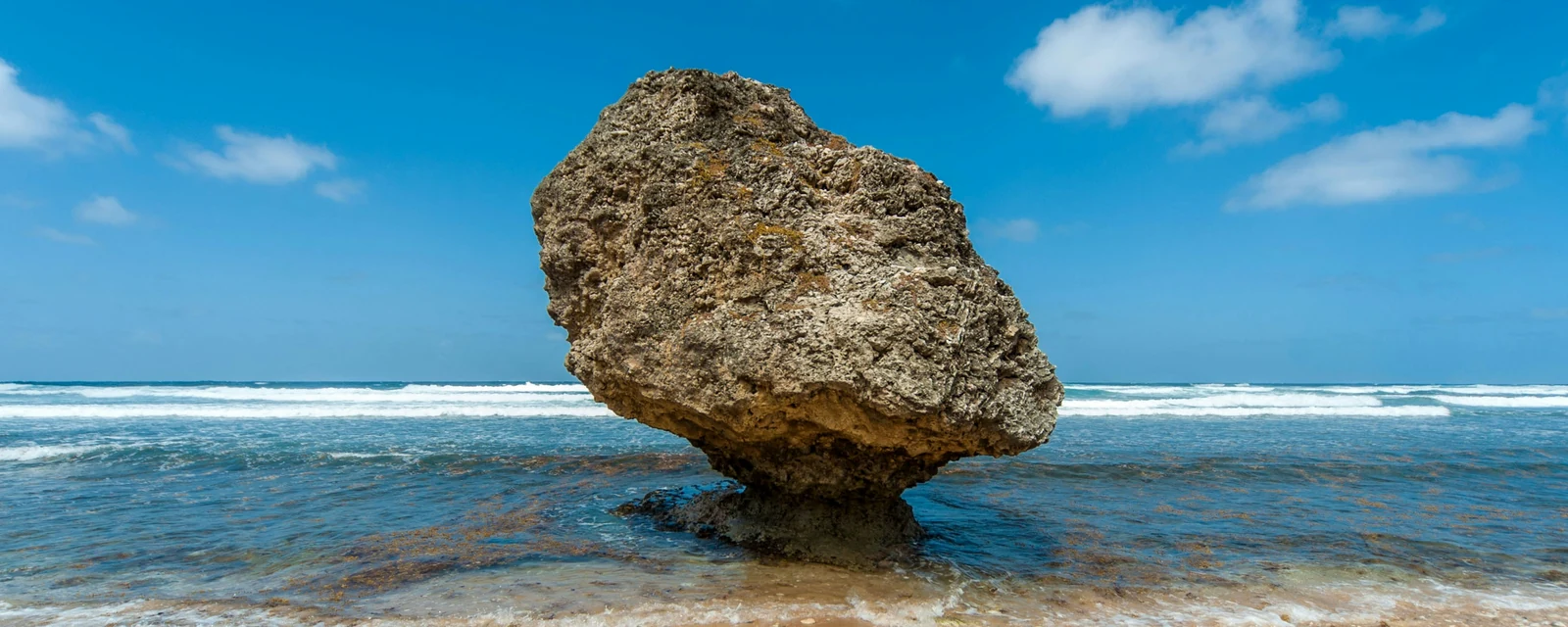 Sunlit balancing rock on the shore at Bathsheba, Barbados, with blue Atlantic surf
