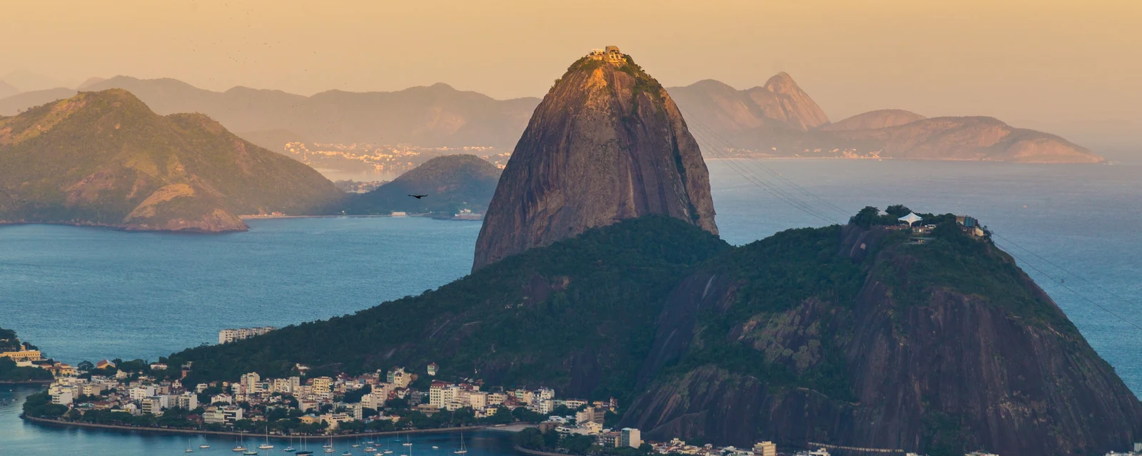Sugarloaf Mountain glowing in golden light above Rio de Janeiro's blue bay and sailboats, Brazil