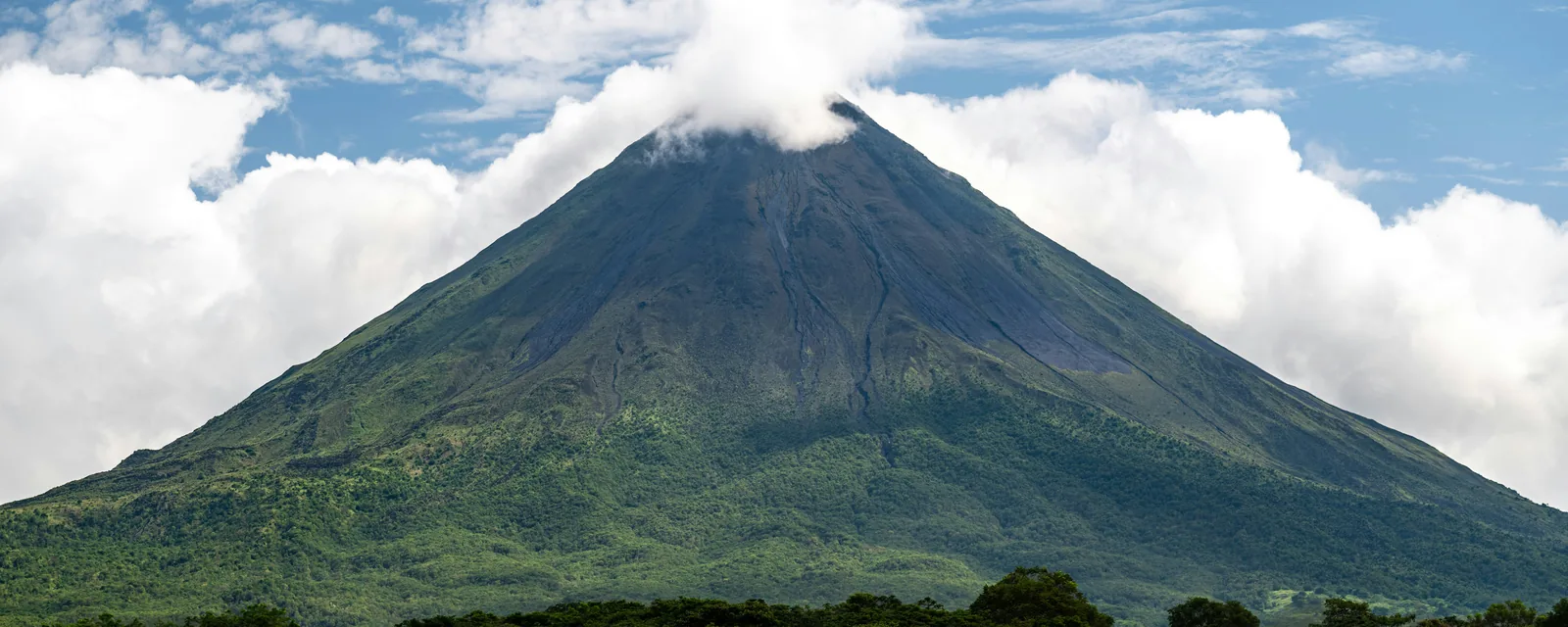 Arenal Volcano rising above green fields and rainforest, Costa Rica
