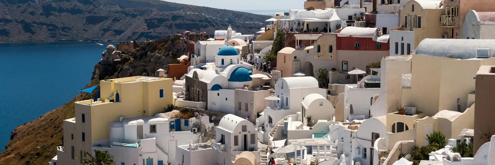 Oia's blue-domed churches and white hillside houses overlooking the Aegean Sea, Santorini, Greece