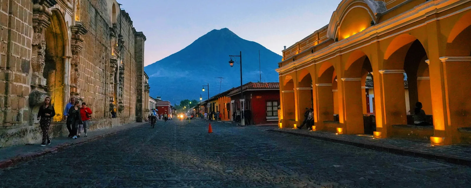 A cobbled street and colonial buildings below a volcano in Guatemala