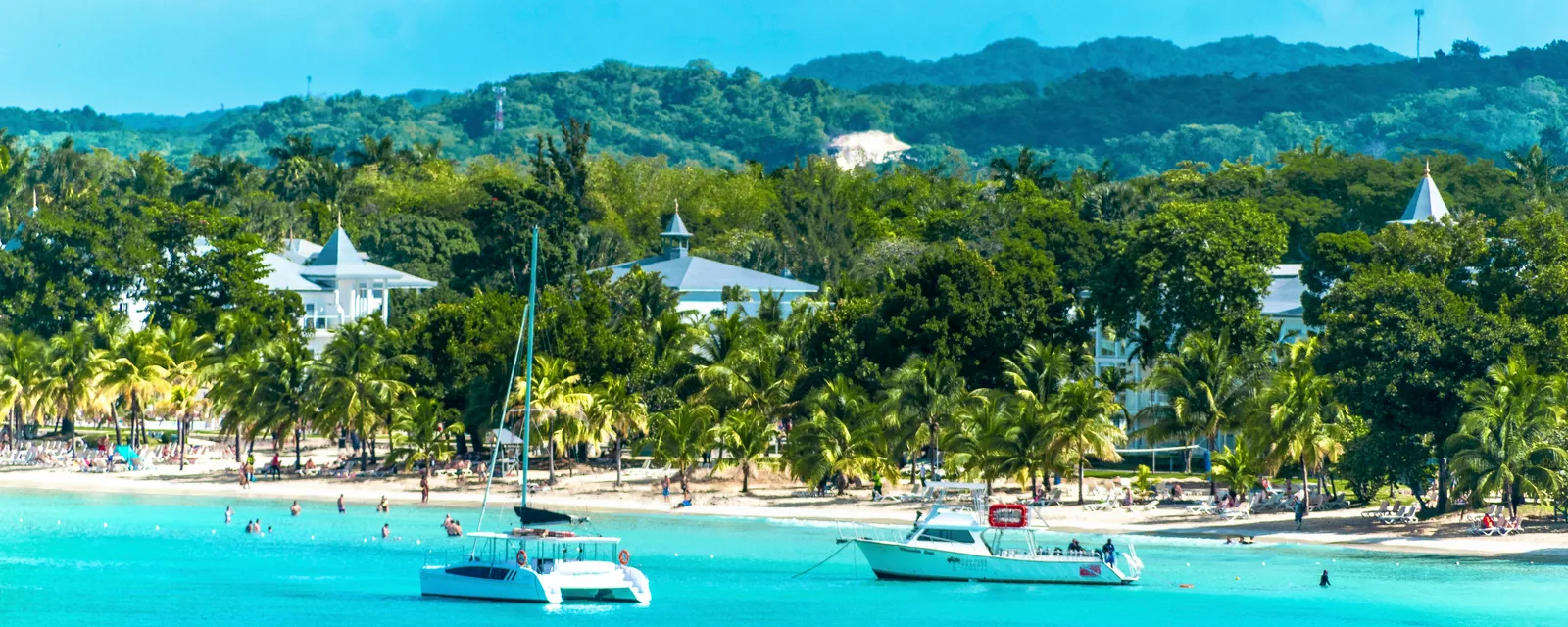Sailboats in turquoise water along Negril's palm-lined coast, Jamaica