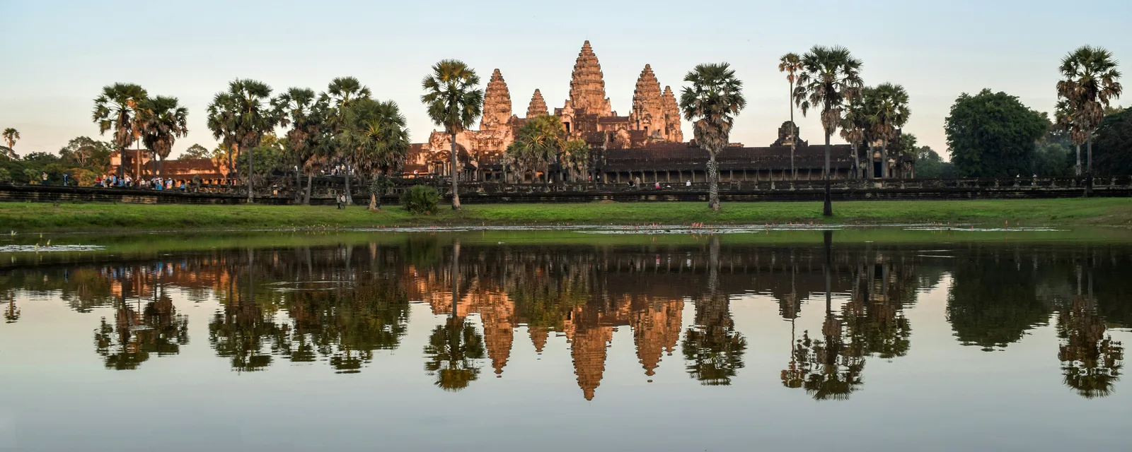 Angkor Wat's towers and palm trees reflected in the water in Cambodia