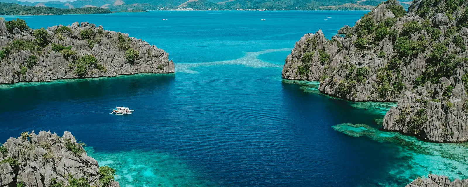 Turquoise water and limestone cliffs around a boat in Coron, Philippines