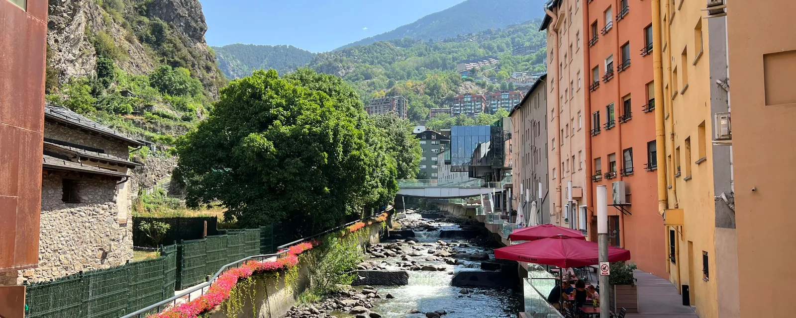 Sunlit river, colorful buildings and Pyrenean mountains in Escaldes-Engordany, Andorra