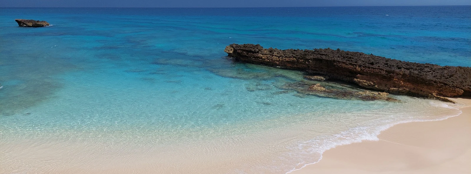 Clear turquoise water washing onto a quiet sandy cove in Anguilla