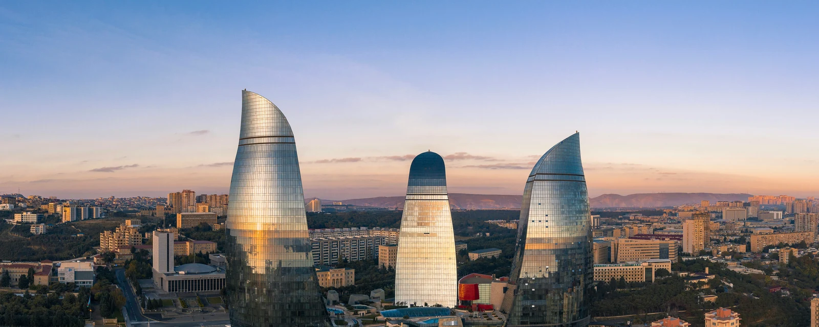 Bakuβs Flame Towers gleaming in warm evening light beneath a blue and pink sky