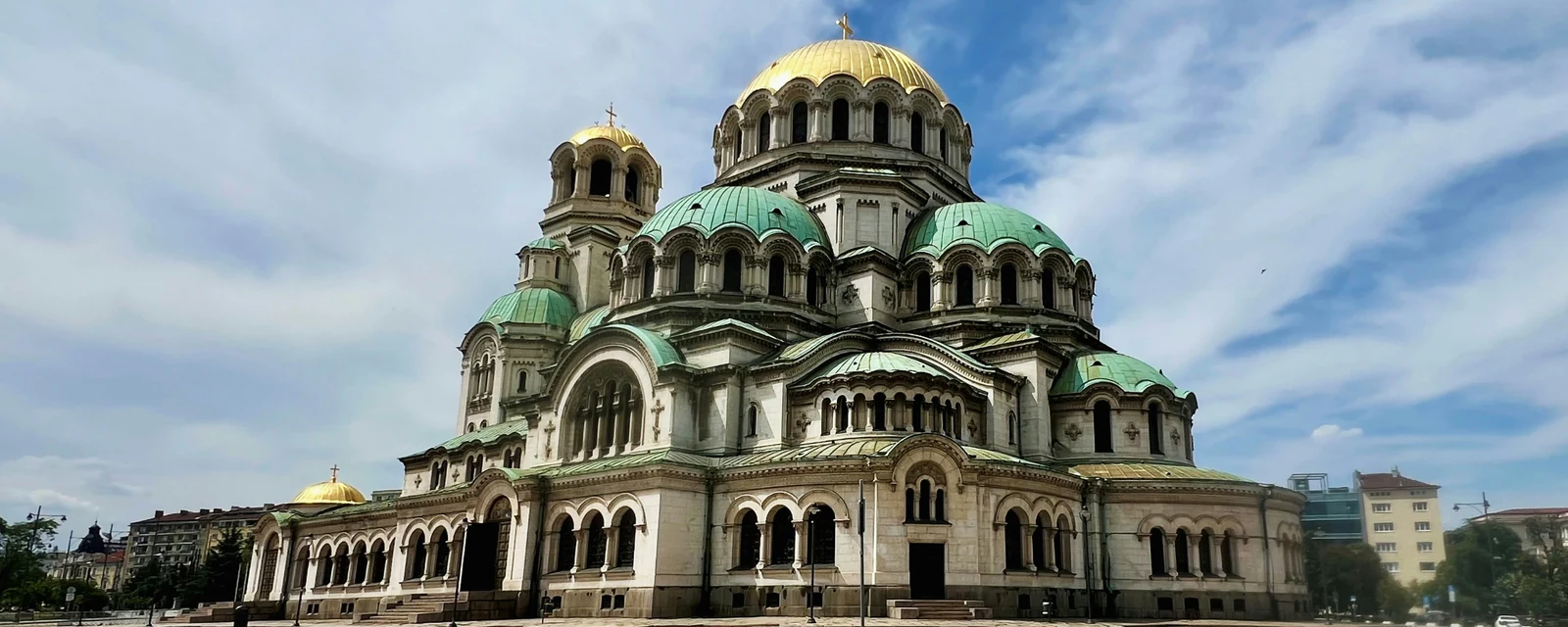 Golden and green domes of Alexander Nevsky Cathedral beneath a blue sky in Sofia, Bulgaria