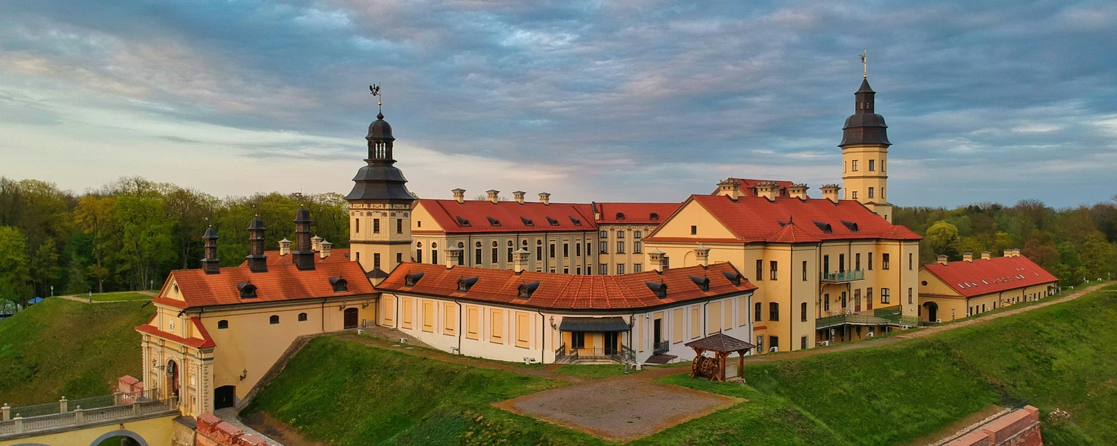 Nesvizh Castle and its green landscaped ramparts beneath a pastel evening sky in Belarus