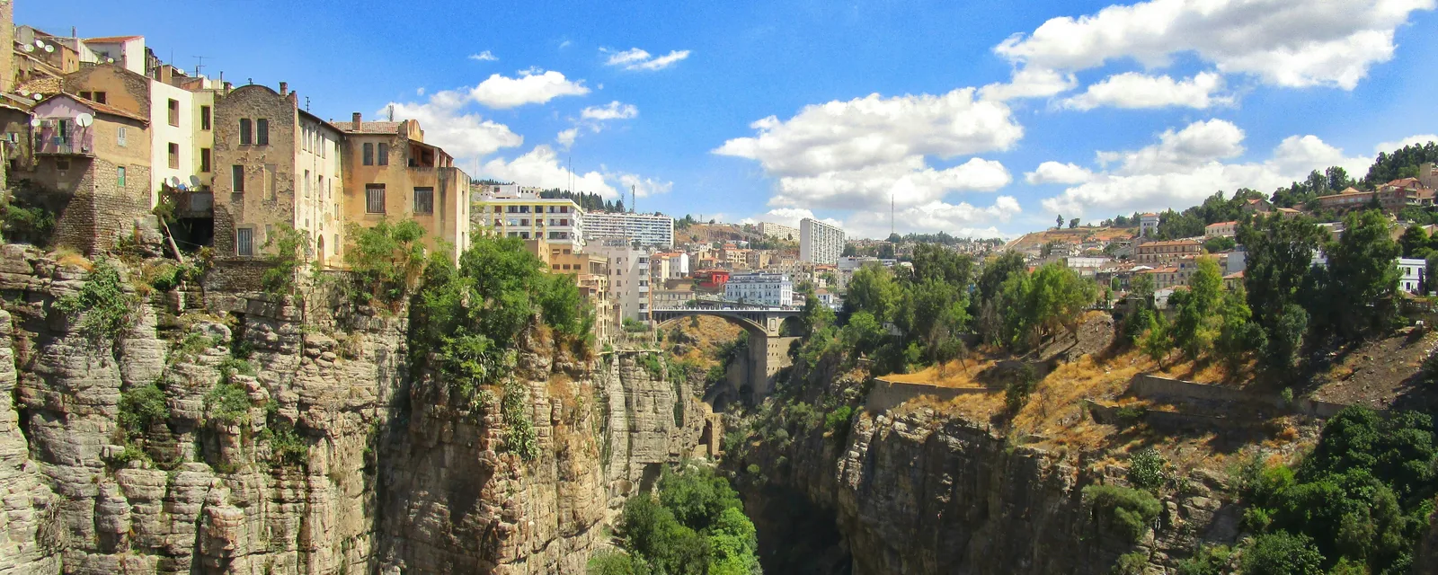 Clifftop buildings and a bridge above the deep green gorge in Constantine, Algeria
