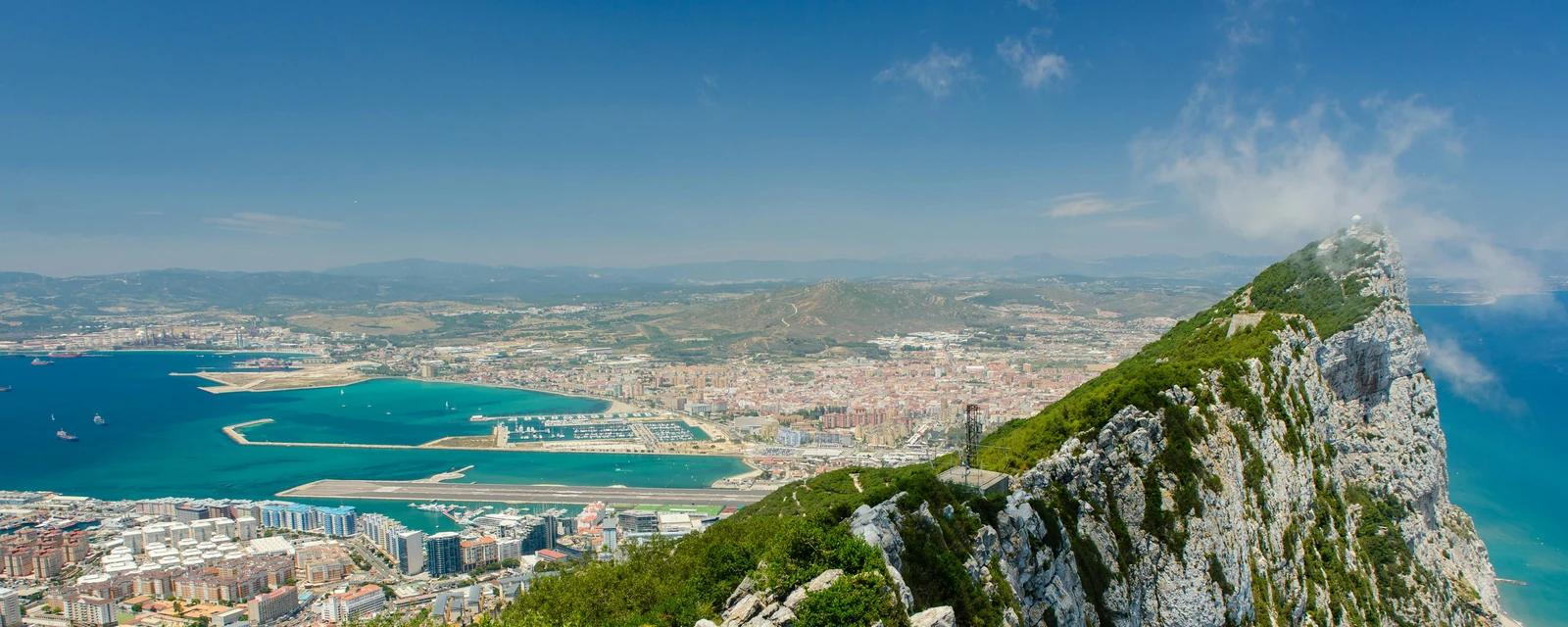 The green ridge of the Rock of Gibraltar overlooking turquoise water and the city