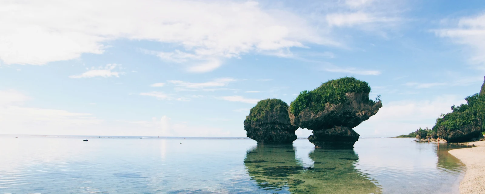 Mushroom-shaped coastal rocks reflected in clear water at Tanguisson Beach, Guam