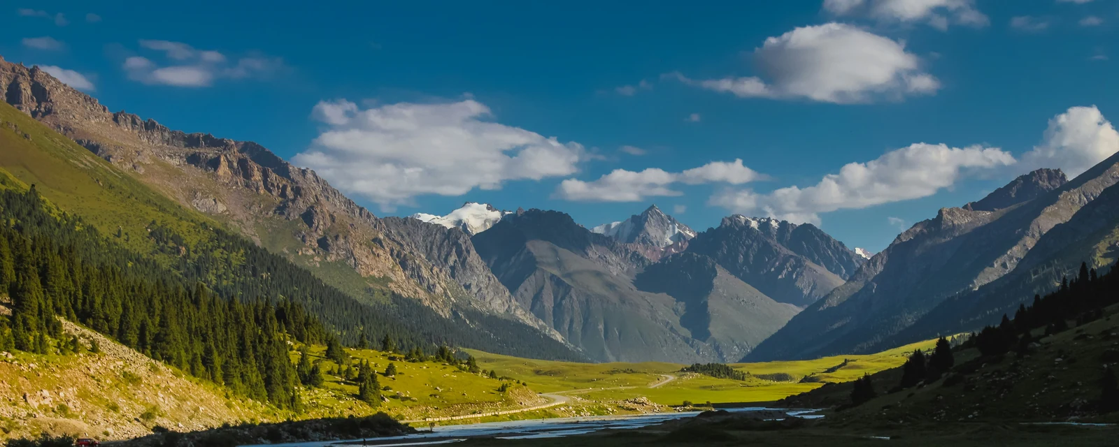 Sunlit mountain valley and winding river near Karakol, Kyrgyzstan