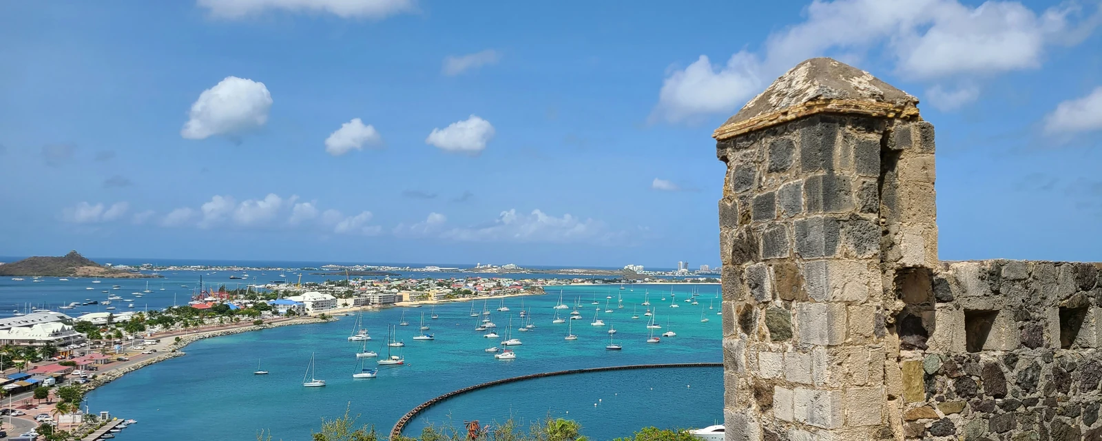 Sunlit stone walls of Fort Louis overlooking sailboats and the turquoise bay at Marigot, Saint Martin