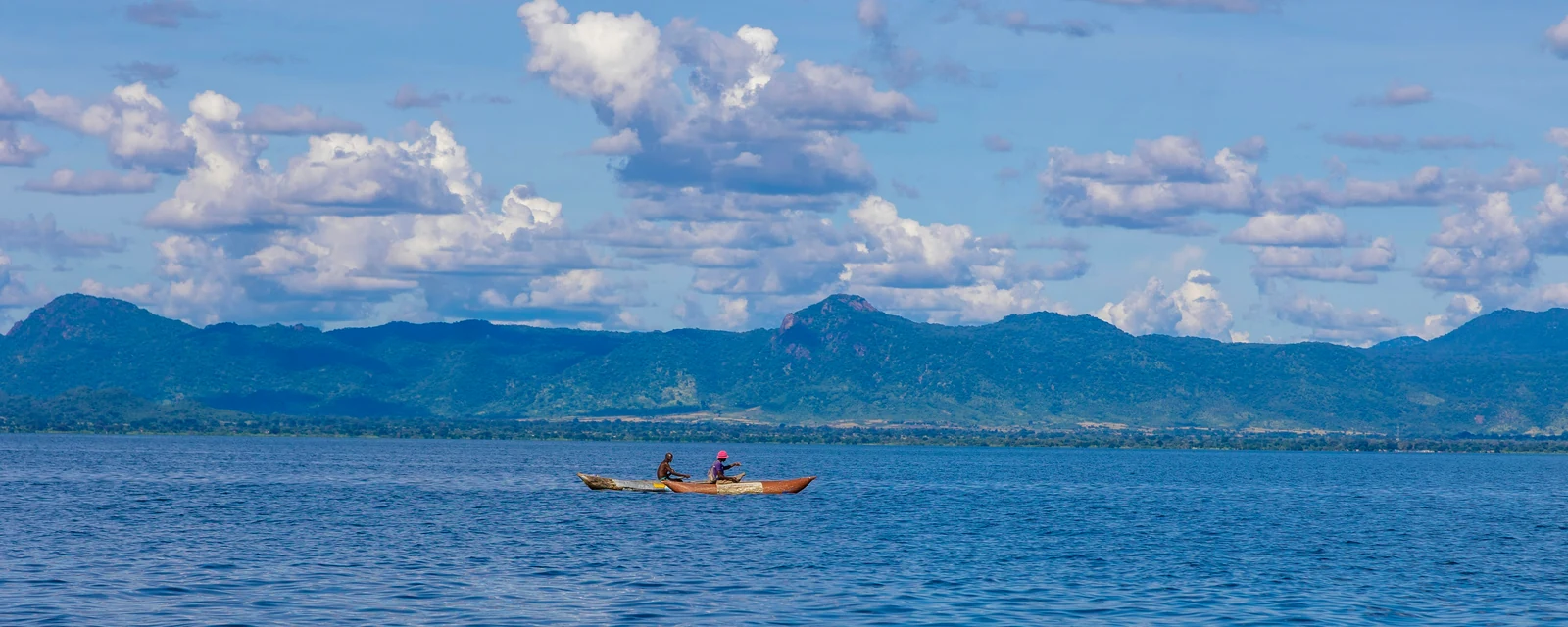 A traditional boat on blue Lake Malawi with mountains beyond