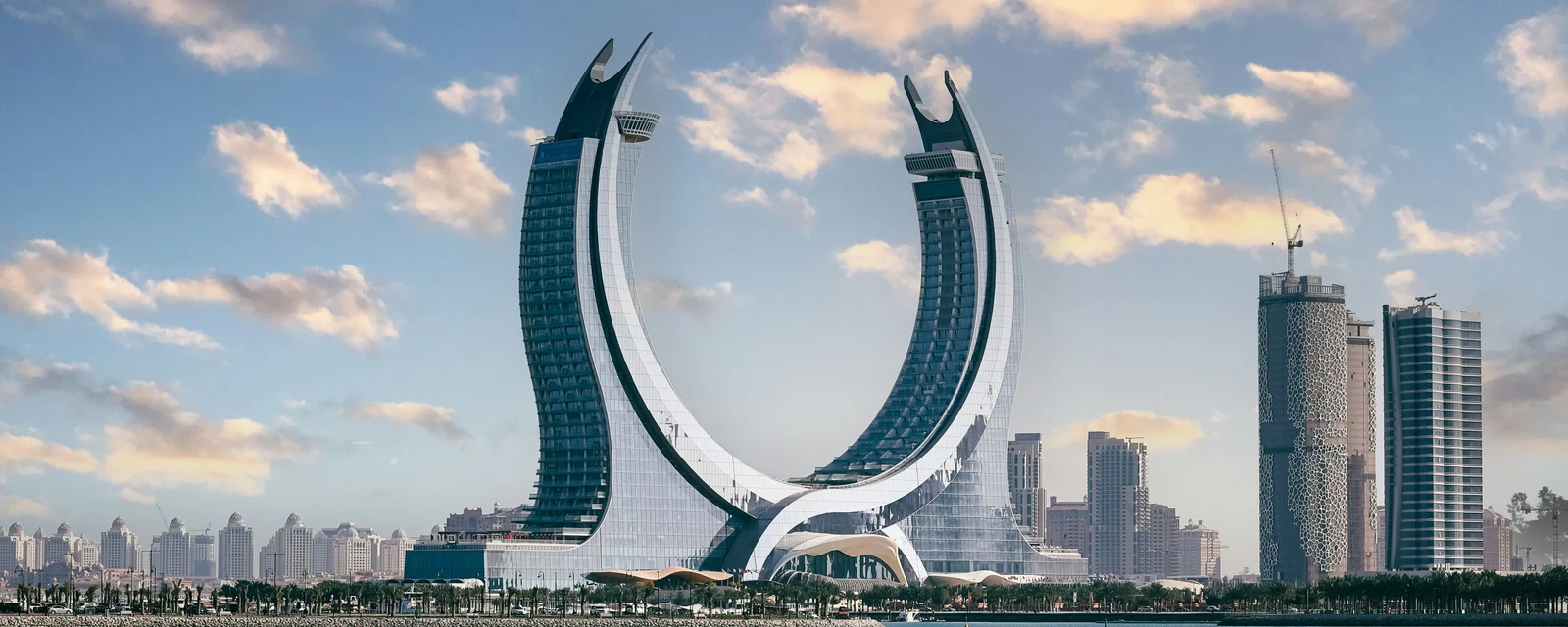 Crescent-shaped Katara Towers above blue waterfront in Lusail, Qatar
