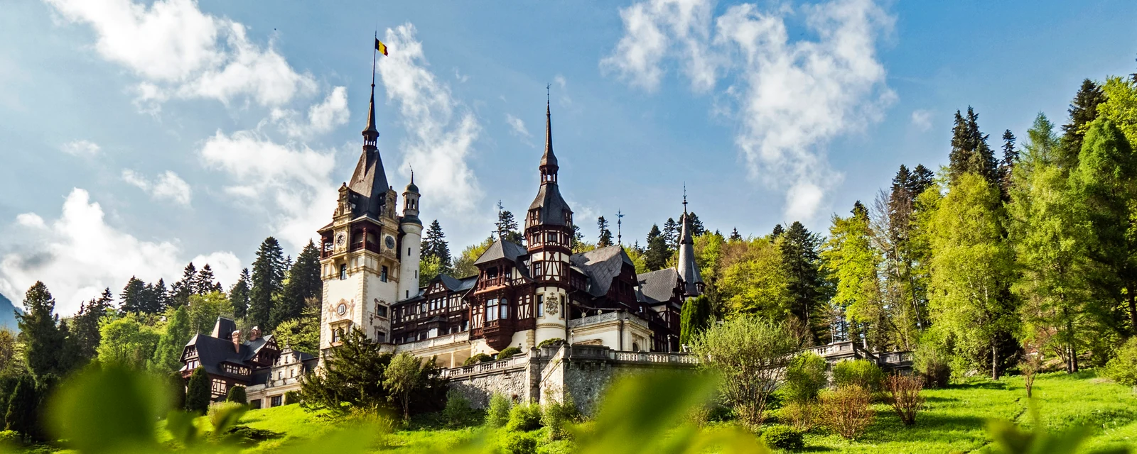 Peleș Castle rising above bright spring gardens in Sinaia, Romania