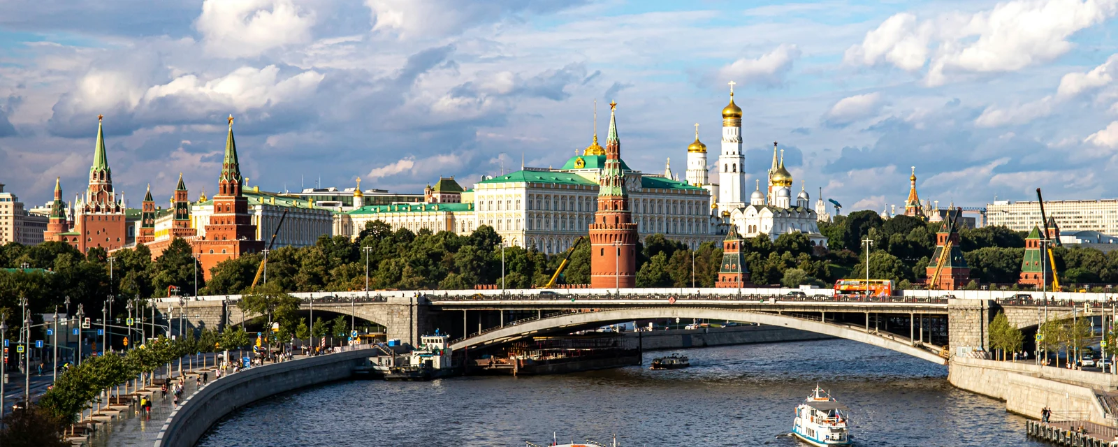 Boats on the Moskva River beneath the red towers and golden domes of the Kremlin in Moscow