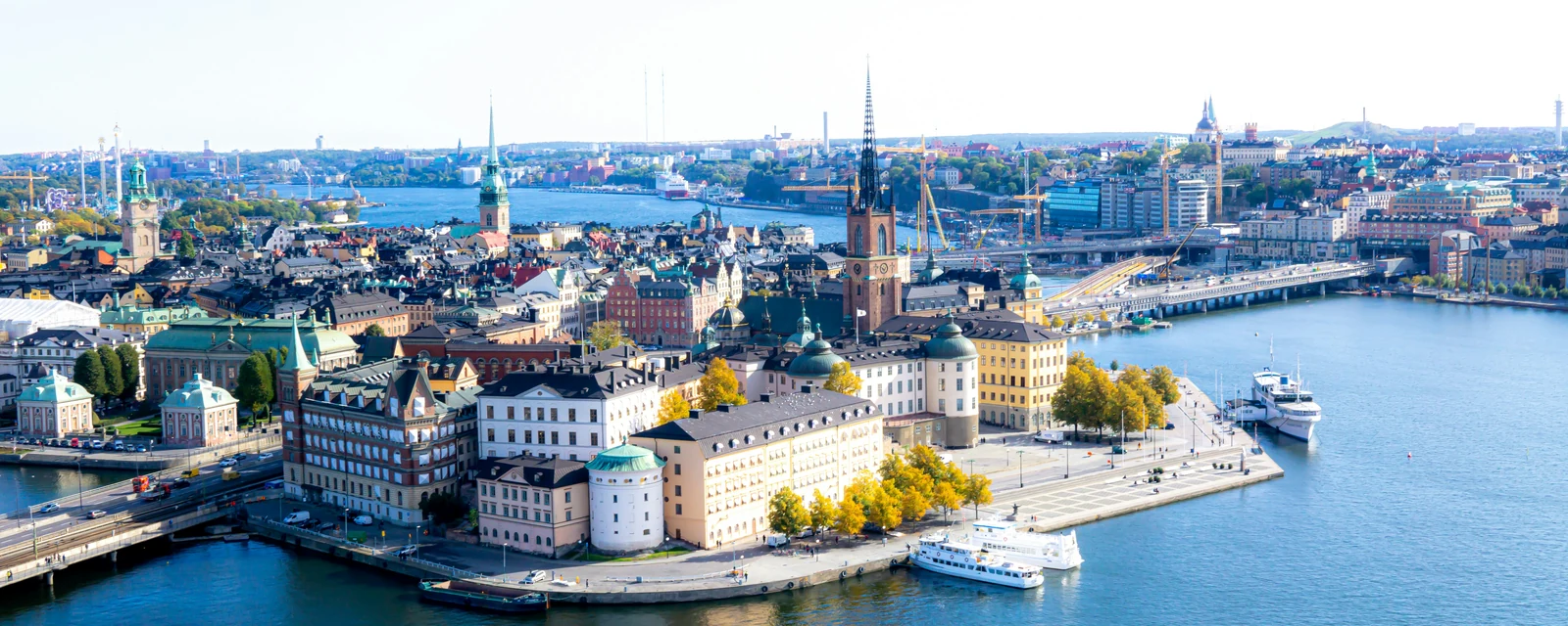 Stockholm's Riddarholmen and Gamla Stan, with church spires, colorful waterfront buildings and boats on blue water, Sweden