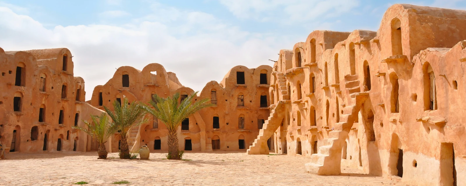 Warm ochre traditional architecture and palms around a courtyard in Tataouine, Tunisia